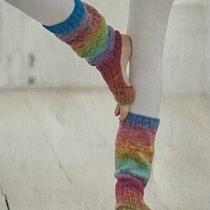 Puede incluir: Un par de polainas de punto de colores con abertura para los dedos. Las polainas están hechas de un hilo suave y texturizado y presentan un patrón de rayas de arcoíris.