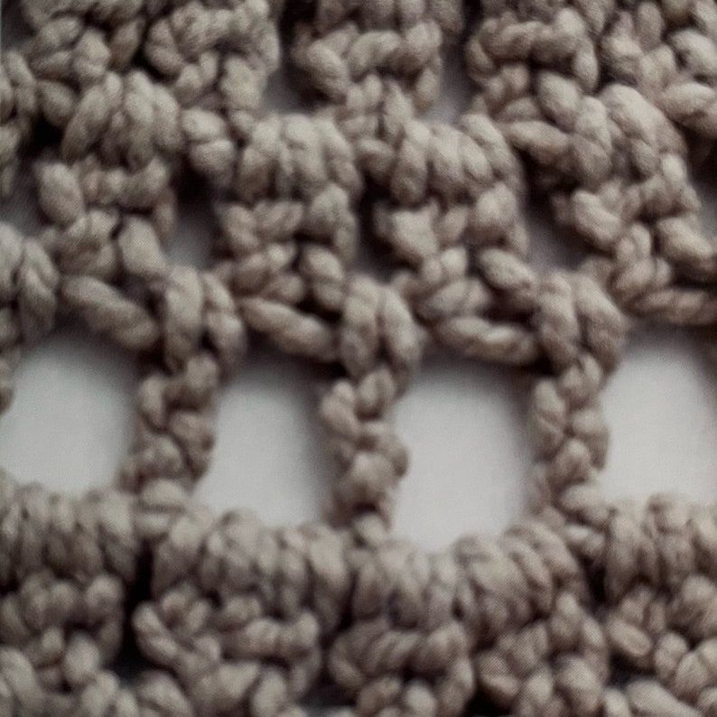 Puede incluir: Primer plano de una tela de crochet de color beige. La tela tiene un patr&oacute;n repetitivo de peque&ntilde;os cuadrados y c&iacute;rculos.