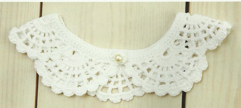 May include: White crocheted collar with a pearl button in the center.