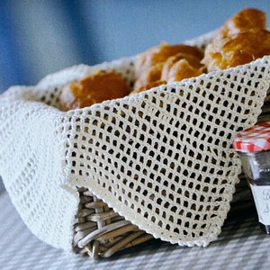 May include: A wicker basket lined with white crocheted fabric filled with pastries and a jar of Bonne Maman Strawberry Conserve.
