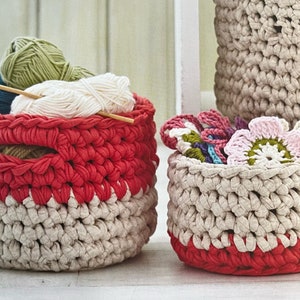 May include: Two crocheted baskets with red and beige stripes. The larger basket is filled with balls of yarn. The smaller basket is filled with crocheted flowers.