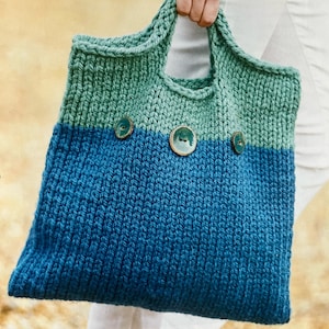 Può includere: Una borsa a mano in maglia di colore blu e verde. La borsa ha tre grandi bottoni sul davanti.