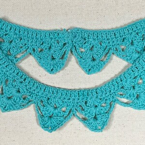 May include: A teal crocheted collar with a scalloped edge. The collar is made of delicate crochet stitches and has a lacy appearance.