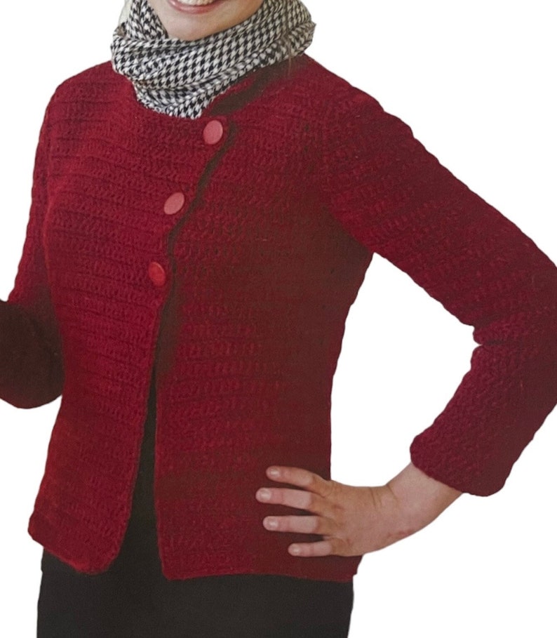 May include: A red crocheted cardigan with a diagonal button closure and three pink buttons. The cardigan has long sleeves and a round neckline.