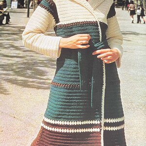 May include: A long, crocheted coat with a wrap style and a belt. The coat is made in a striped pattern of white, brown, and green yarn.