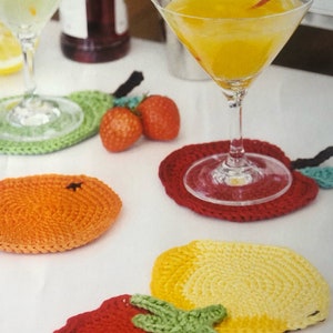 Könnte beinhalten: Häkeluntersetzer in Form von Früchten, darunter eine Birne, eine Orange, ein Apfel und eine Zitrone. Die Untersetzer sind aus buntem Garn gefertigt und perfekt, um Ihrem Zuhause einen Hauch von Verspieltheit zu verleihen.
