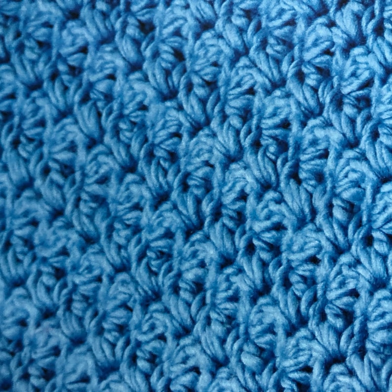 May include: Close-up of a blue crocheted fabric with a textured surface.