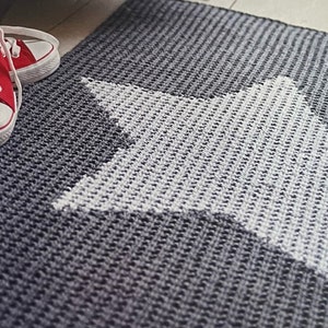 May include: A gray and white crocheted rug with a large white star in the center.