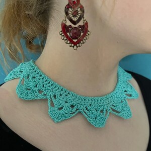 May include: A turquoise crocheted collar necklace with a scalloped edge.