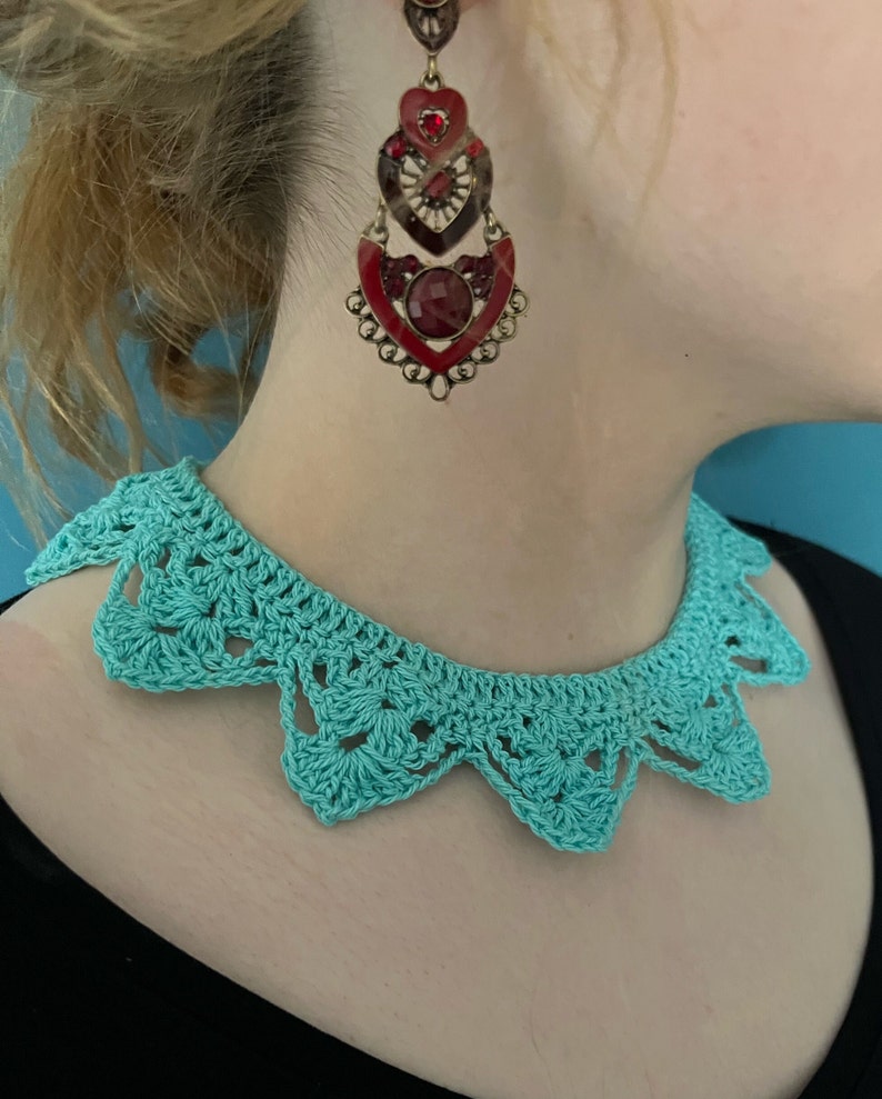 May include: A turquoise crocheted collar necklace with a scalloped edge.