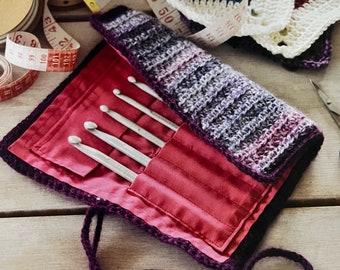 May include: A purple crocheted case with a red satin lining holds a set of six silver crochet hooks.