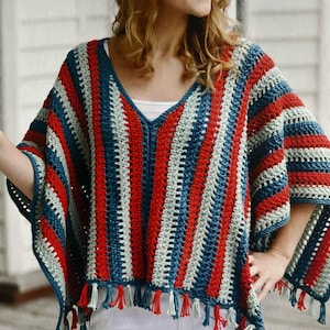 Peut inclure: Un poncho en crochet avec des rayures rouges, bleues et vertes et des franges. Le poncho a un col en V et est réalisé avec un point texturé.
