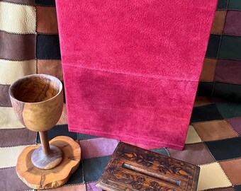 May include: A bright red suede-effect storage bin, a wooden chalice, and a decorative wooden box with inlaid floral patterns are displayed. They are set on a patchwork leather surface.