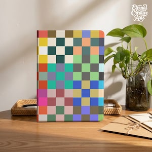 May include: A rectangular notebook featuring a vibrant grid pattern composed of multicolored squares in shades of yellow, red, pink, green, blue, purple, and brown. The cover displays a repeating geometric design with a matte finish and clean edges.
