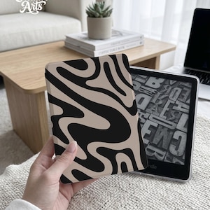 May include: A black and tan Kindle cover with a wavy pattern is held in front of a Kindle device. The cover design is repeated on the cover. The words "Eternal Creative Arts" are in the upper left corner.