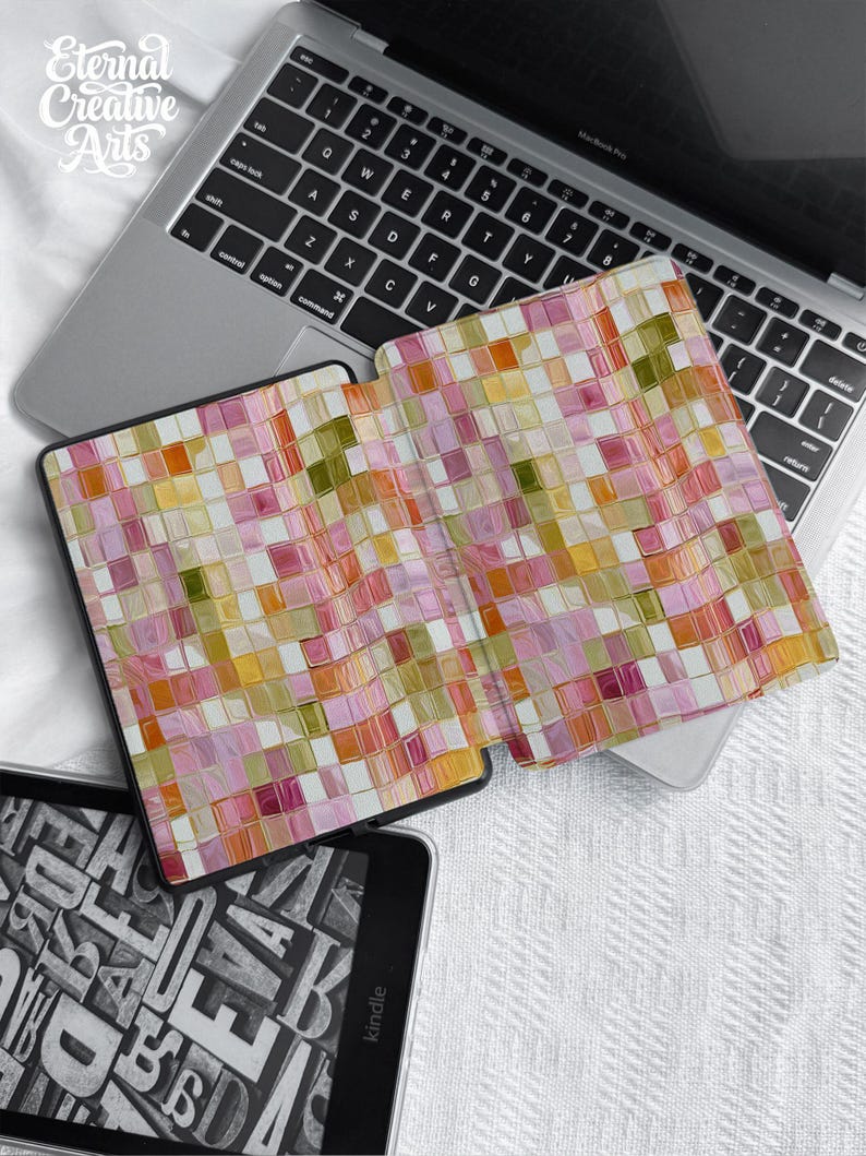 May include: A protective e-reader cover featuring a vibrant, multi-colored mosaic tile pattern in shades of pink, orange, yellow, and olive green. The cover is open, displaying a grid of small, glossy squares, and is positioned atop a silver laptop.