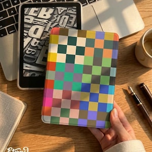 Puede incluir: Una funda de lector electrónico con un patrón de cuadros coloridos en tonos rosa, verde, azul y amarillo. La funda se sostiene cerca de un portátil y una taza de café. El texto "Eternal Creative Arts" es visible en la esquina inferior izquierda.