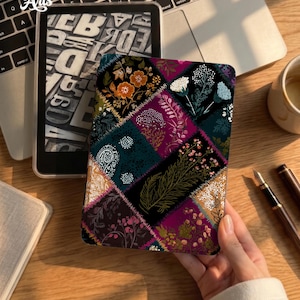 May include: A rectangular e-reader case featuring a patchwork design of various floral and botanical illustrations in shades of deep magenta, dark teal, gold, and black, with visible stitched-style borders separating each patterned section.