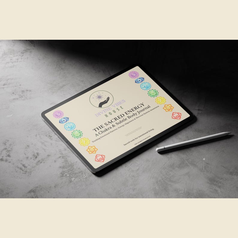 May include: A digital tablet displaying "THE SACRED ENERGY" journal with chakra symbols. The journal is designed to track emotional patterns and energy alignment. A white stylus rests beside the tablet on a gray surface.