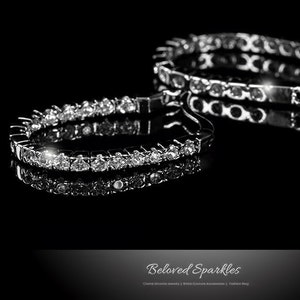 Puede incluir: Dos pulseras plateadas con brillantes gemas transparentes sobre un fondo negro. Las pulseras se reflejan en la superficie brillante. La imagen incluye el texto "Beloved Sparkles".