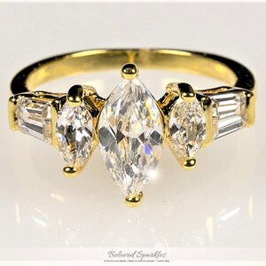 May include: A gold ring with three marquise-shaped clear stones and two baguette-shaped clear stones.