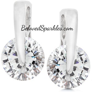 May include: A pair of silver earrings with a clear round crystal stone set in each earring. The earrings have a simple design with a curved silver post that goes through the earlobe.