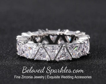 May include: A silver ring with a row of triangular clear cubic zirconia stones. The ring is on a black background.