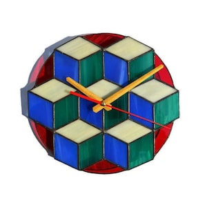 May include: A circular stained glass wall clock featuring a geometric pattern of interconnected cubes in shades of blue, green, and off-white. The clock has two yellow hour and minute hands and a thin red second hand centered on the glass surface.