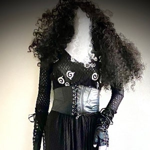 May include: A black gothic dress with a long skirt and a fitted bodice. The bodice has a black corset and a top with white spiral designs. The outfit includes long gloves and a curly black wig.