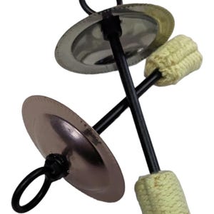 May include: A pair of black metal cymbals with a yellow wick attached to each handle. The cymbals are connected by a black metal rod.