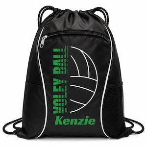 May include: A black drawstring backpack featuring a white volleyball graphic, the green text "VOLLEY BALL" and the name "Kenzie" in green. The bag includes a front zippered pocket, white piping accents, and a black mesh side pocket for storage.