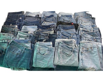 Könnte beinhalten: Eine große Sammlung gefalteter Jeanshosen in verschiedenen Blautönen, von hellen Waschungen bis zu dunklem Indigo. Der Stapel enthält mehrere Hosen mit unterschiedlichen Texturen, Waschungen und abgenutzten Details, die alle ordentlich angeordnet sind.