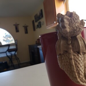 Puede incluir: Una taza de cer&aacute;mica roja con una figurita de drag&oacute;n marr&oacute;n unida al lado. El drag&oacute;n est&aacute; mirando la taza y tiene un cuerpo texturizado y escamoso.