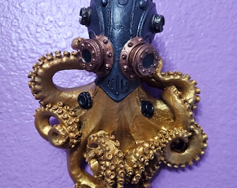 Może przedstawiać: Złota i czarna figurka steampunkowa ośmiornicy z detaliczną głową i wieloma mackami.