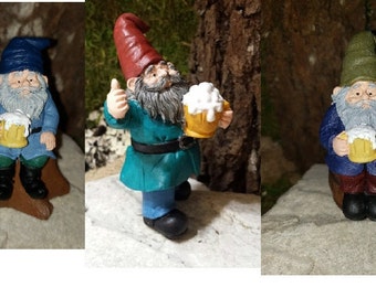 Peut inclure: Trois nains miniatures tenant des mugs de bière. Les nains portent des chapeaux et des vêtements de différentes couleurs. Un nain est assis sur une souche d'arbre.