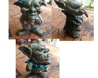Puede incluir: Tres figuras de duendes verdes con orejas grandes y narices puntiagudas. Los duendes llevan diferentes atuendos y tienen diferentes expresiones faciales.