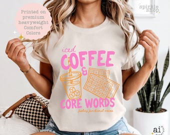 Op de afbeelding: Een crèmekleurig t-shirt met een afbeelding met de roze tekst "iced COFFEE & CORE WORDS" en de oranje tekst "fueling functional voices". Het ontwerp bevat een illustratie van een ijskoffie en een communicatiebord.