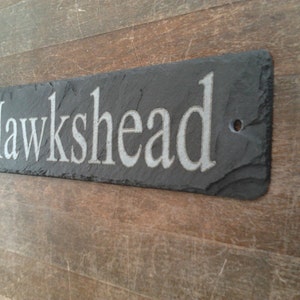 Può includere: Un cartello in ardesia nera con il nome "Hawkshead" inciso in lettere bianche.