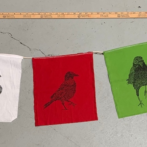 May include: A string of five fabric flags with black crow silhouettes printed on them. The flags are blue, white, red, green, and yellow.