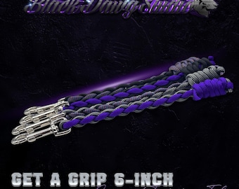 May include: Three 15 cm paracord training tabs featuring a braided design in black, grey, and purple. Each tab includes a silver-toned metal swivel snap hook at one end. The text Black Dawg Studio and GET A GRIP 6-INCH Paracord Training Tab is visible.