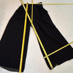 Puede incluir: Pantalones negros de pierna ancha con cintura el&aacute;stica. Una cinta m&eacute;trica amarilla se coloca sobre los pantalones para mostrar las medidas. Los pantalones est&aacute;n hechos de un material ligero.