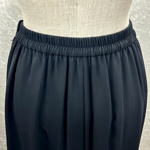 Puede incluir: Primer plano de un pantal&oacute;n negro con cintura el&aacute;stica. La tela es suave y cae desde la cintura. El pantal&oacute;n se muestra en un maniqu&iacute;.