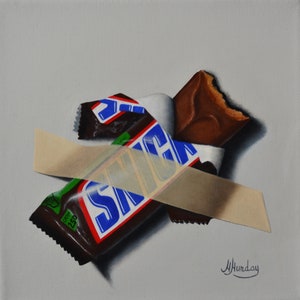 May include: A partially unwrapped Snickers candy bar with a bite taken out of it, taped to a white background. The candy bar is wrapped in blue, red, and green foil with the word "SNICKERS" printed on it.
