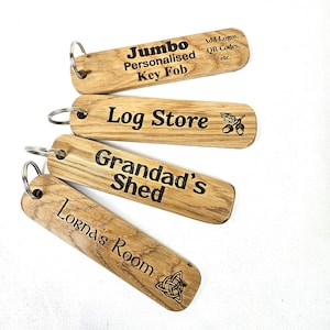 May include: Four rectangular wooden key fobs with metal rings. The top fob reads Jumbo Personalised Key Fob Add Logos QR Codes etc. The second reads Log Store with an acorn icon. The third reads Grandad's Shed. The bottom reads Lorna's Room with a knot icon.