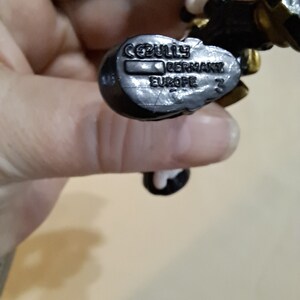 May include: Close-up of a black plastic toy figure with a white and gold design. The figure has a label on the bottom that reads "CEBULY GERMANY EUROPE 3".