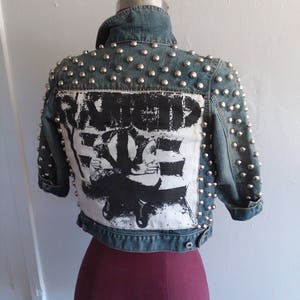 May include: A blue denim jacket with silver studs and a black and white graphic on the back that says "Another Girl, Another Planet".