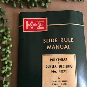 May include: A green and gold manual for a slide rule called the "PolyPhase Duplex Decitrig No. 4071" by Lyman M. Kells, Willis F. Kern, and James R. Bland. The manual is published by Keuffel & Esser Co.