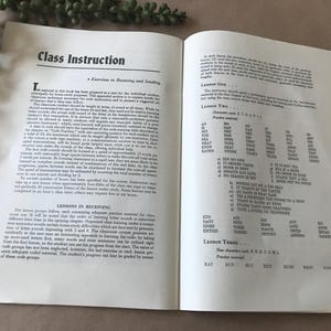 May include: Open book with text titled "Class Instruction" and "Lessons in Receiving." The pages display text and lists of words and phrases for learning. The book is open to pages 38 and 39.