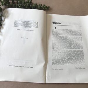 May include: An open book with the title "Foreword" on the right page. The left page has text and the words "Ninth Edition." Green leafy sprigs are in the upper left corner.