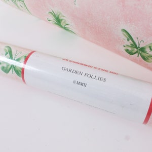 May include: A roll of pink wallpaper with a green butterfly pattern. The label reads "Garden Follies &copy;MMII".